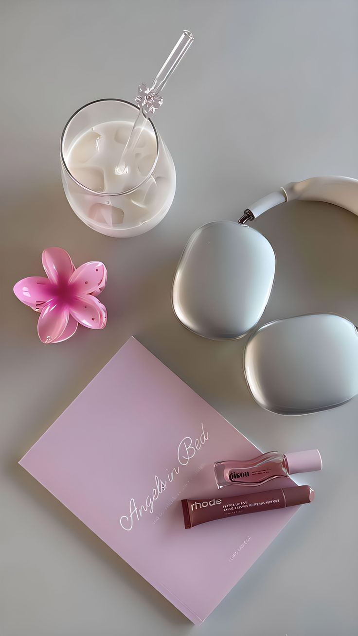 Pink beauty flat lay with cosmetics, flower, headphones and iced drink